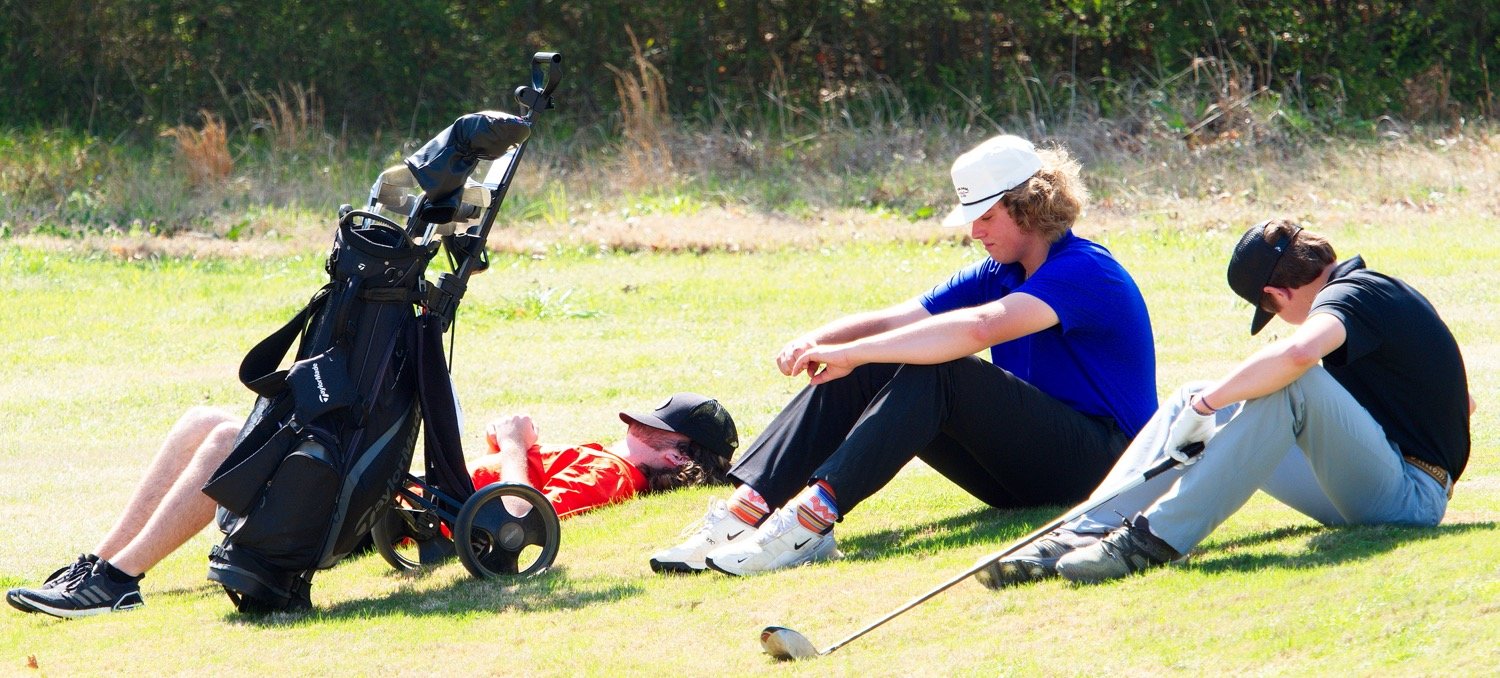Mineola's Jack Heard and Quitman's Parker Simpkins (left and center) take a moment to rest as they wait on the tee for the group in front of them to clear the fairway. [see some swings]